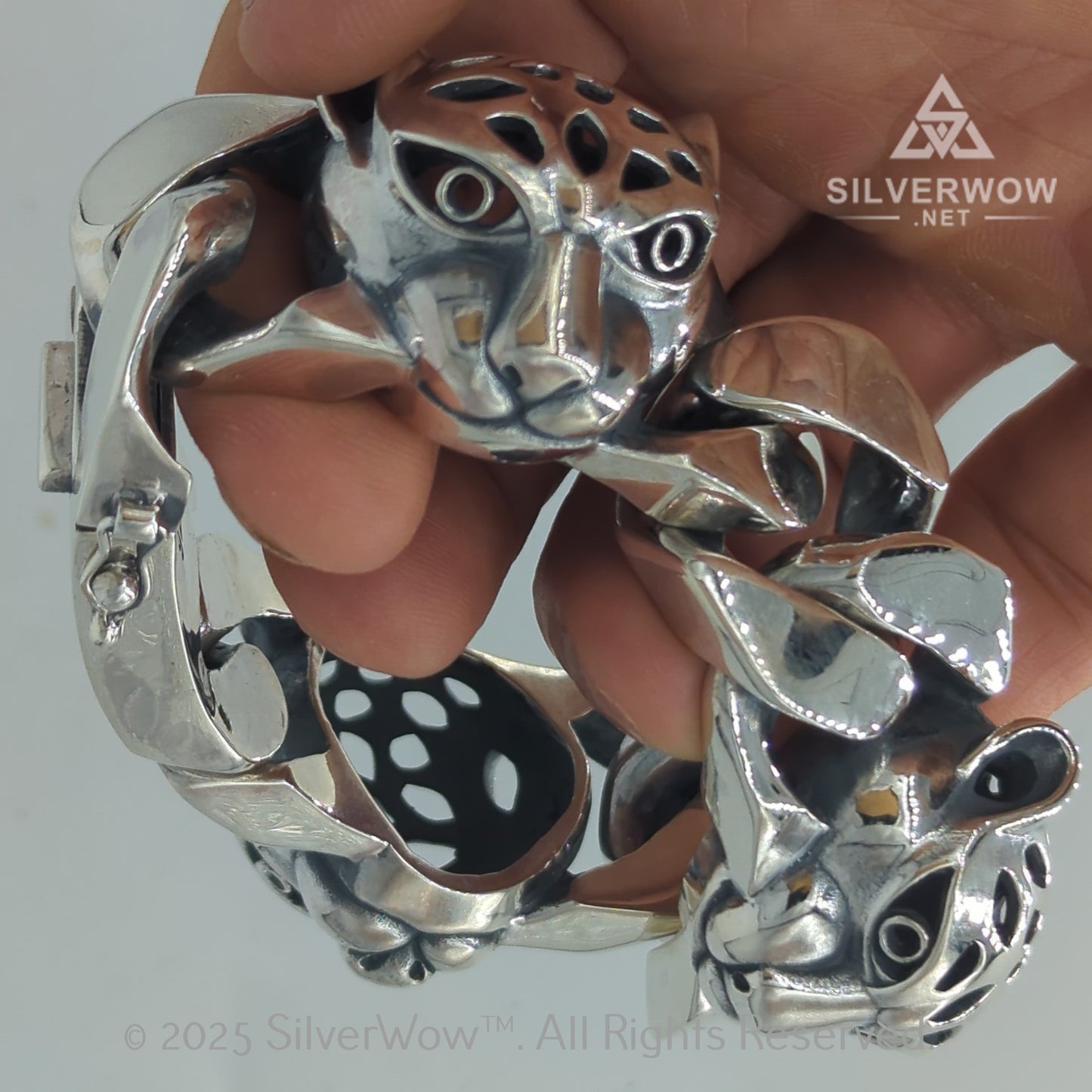 Closeup of leopard bracelet heads with black eyes and thick silver links