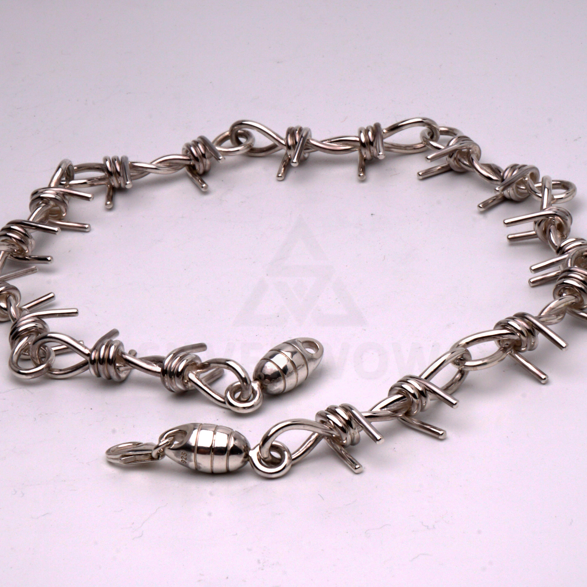 Barbed wire necklace in solid silver laid flat in a circular shape to show design
