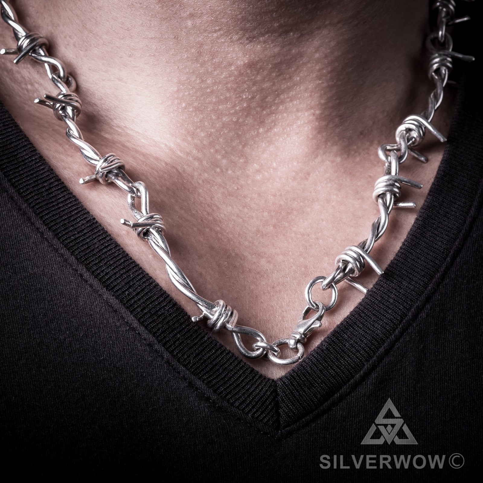 Polished silver barbed wire necklace worn across collarbone for men
