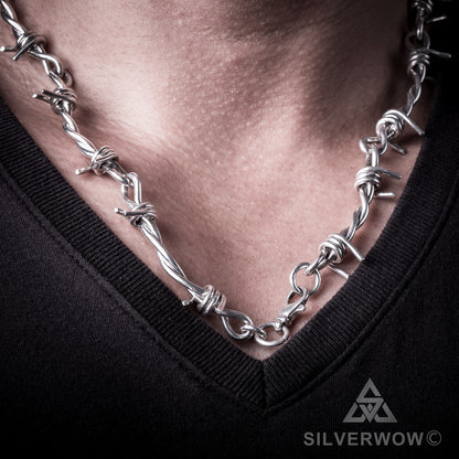 Polished silver barbed wire necklace worn across collarbone for men
